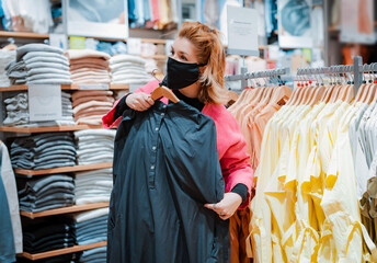 beautiful woman with phone bright pink shopping Mall coat with black protective mask on her face from virus infected air.