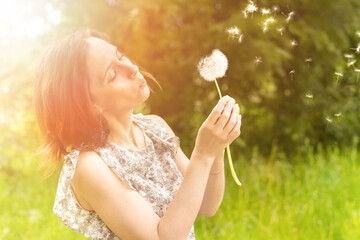 Girl blows a dandelion in nature and walks in park