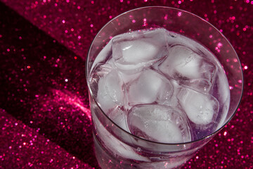 Glass with ice and refreshing drink, on a red background.