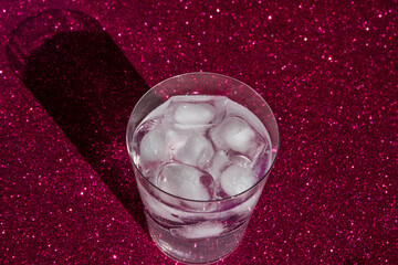 Glass with ice and refreshing drink, on a red background.
