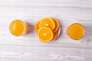 sliced fresh citruses and orange juice on the light rustic wooden surface. top view