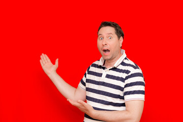 Cheerful man wearing striped t shirt pointing at palm, showing product