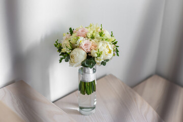 Wedding bouquet in a glass vase on the stairs near the wall.