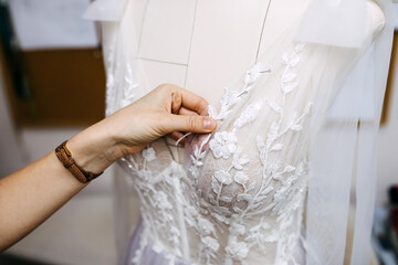 Close-up of work process of a fashion designer at her studio. Hand sewing bridal gown / dress...