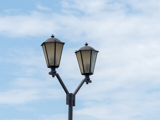 Fototapeta na wymiar Iron black retro street lights against the blue sky with white clouds
