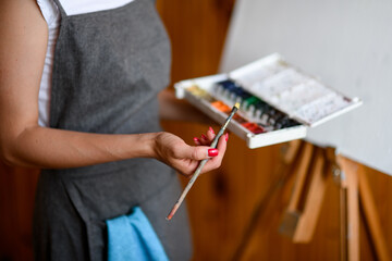 watercolor paints and brush for painting in the hands of woman artist