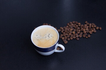 cup of espresso and cofee seeds on black background