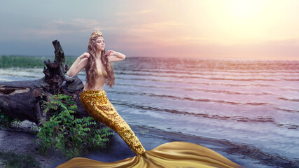 Fantasy woman real mermaid with trident myth goddess of sea with golden tail sitting in sunset on...