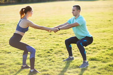 Young sportive couple doing fitness exercises on warm summer day outdoors.