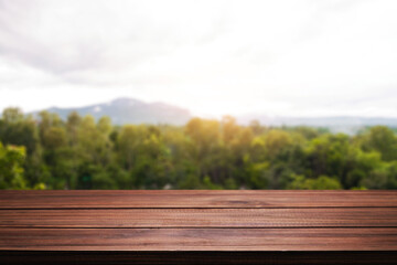 Empty wooden desk space and blurry background of mountain or hill.