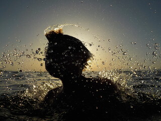 Silhouette of a child playing with the water in the sea 