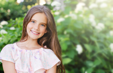 Portrait of adorable smiling little girl child in summer day. Happy preteen in the park
