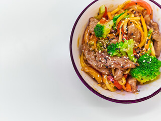 Udon noodles with meat in a plate on a white surface. With vegetables greens