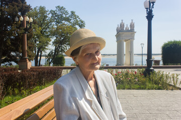 Elderly woman  taking a walk. Senior woman in straw hat on a park bench. Social distance.