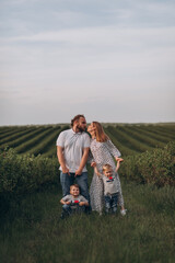 Big young happy family in the field on the nature. Mom, dad and 2 sons are having fun, running, fooling around together. Happiness and smiles around