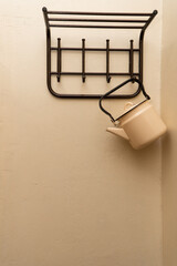 an old yellow metal kettle hangs on the wall on an empty clothes hanger