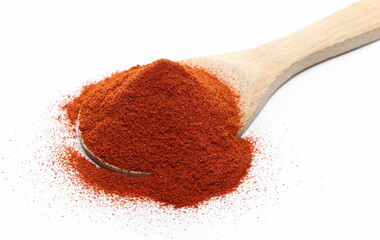 Red paprika, pepper powder pile with wooden spoon isolated on white background