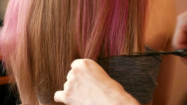 Home hairdressing salon. Close-up of father's hands cutting the long hair of an adult Caucasian daughter. Self-isolation lifestyle