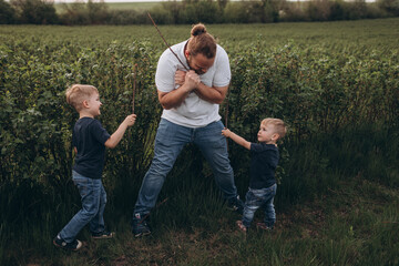 Big young happy family in the field on the nature. Mom, dad and 2 sons are having fun, running, fooling around together. Happiness and smiles around