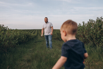 Big young happy family in the field on the nature. Mom, dad and 2 sons are having fun, running, fooling around together. Happiness and smiles around