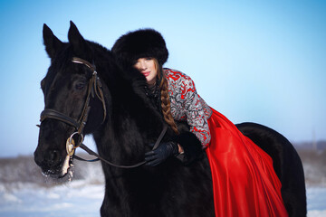 beautiful woman in  red dress, is of black horse in winter 