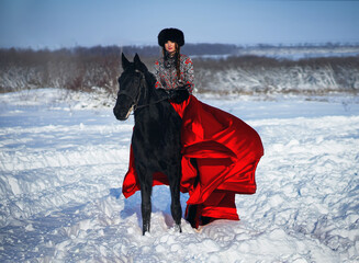 beautiful woman in  red dress, is of black horse in winter 