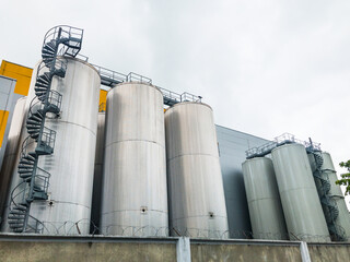 Big metal insulated cold storage containers with spiral staircase and bridge. Designed for storing substances at constant temperatures. 