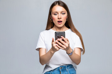 Exciting woman reading text message on the phone isolated on gray background