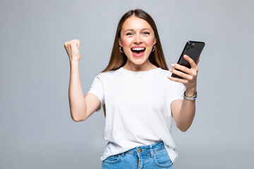 Fototapeta premium Young woman with a mobile phone celebrating a victory isolated on white background