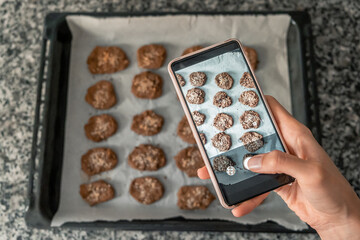Woman hands taking a photo of a fresh batch of healthy oat cookies.