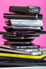 outdated and modern models of smartphones and mobile phones. dirty, broken and old smartphones on a pink background