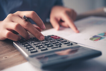 close up The business person is sitting on a calculator with a graph in the office of finance accounting concept