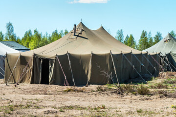 old soldiers canvas tents torn in the wind in the field. Tent city on military exercises