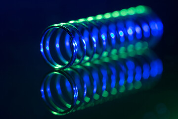 Steel spring in green and blue light close up