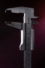 Old caliper in backlight with red light on the background.