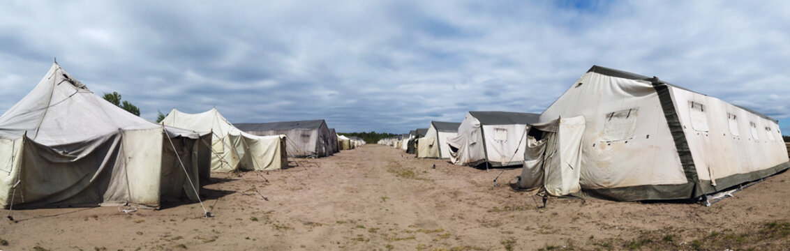 old soldiers canvas tents torn in the wind in the field. Tent city on military exercises