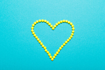 Symbol heart from yellow pills medicament on blue background 