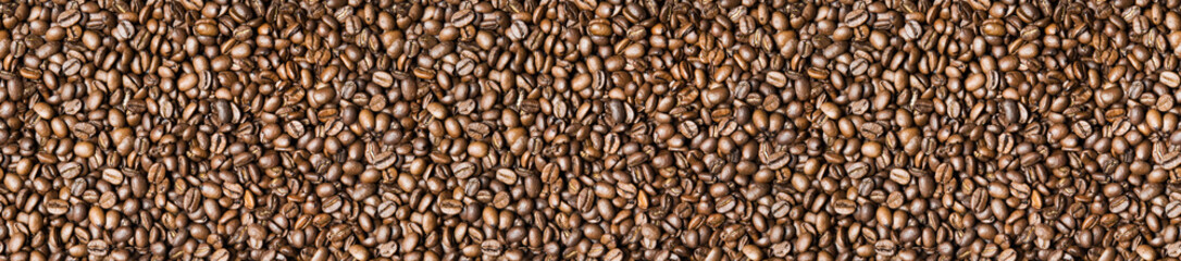 Fototapeta premium Roasted coffee beans background - full frame detail. Close up of a brown surface texture of aroma black caffeine drink ingredient for coffee beverage. Wide format banner