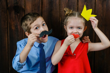 A kid with props for a photo booth. Children with the requisite mustache on wooden background....