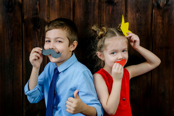 A kid with props for a photo booth. Children with the requisite mustache on wooden background....