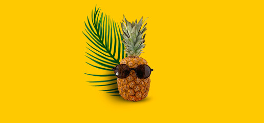 Summer abstract marine background for travel. Pineapple with glasses, a summer hat, palm branches. Banner, close-up.