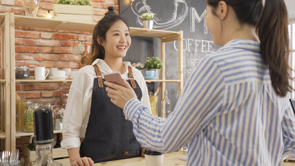 Young beautiful woman customer making wireless and contactless payment using mobile phone in cafe...