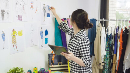 Young fashion designer asian japanese woman looking at her tablet thinking details creating in...