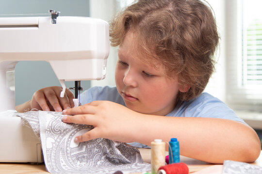 Boy using sewing machine at home to make crafts