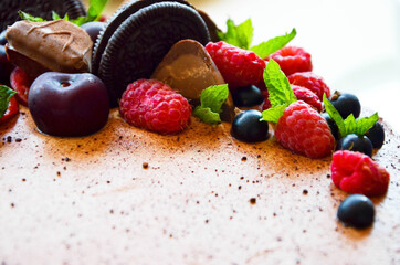 Chocolate cake in cocoa from above berries raspberries, black currant, biscuits, sweets on a round plate on the table. Cake slice, berries in macro. Birthday cake number 2. Top view, side view. 