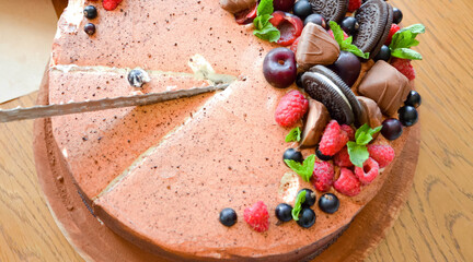 Chocolate cake in cocoa from above berries raspberries, black currant, biscuits, sweets on a round plate on the table. Cake slice, berries in macro. Birthday cake number 2. Top view, side view. 