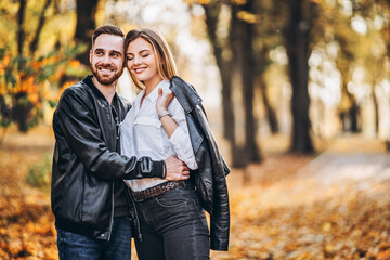 Man and woman hugging and smiling in the background of autumn park.