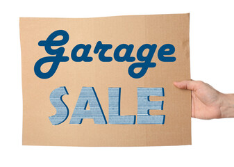 Woman holding piece of cardboard with phrase GARAGE SALE on white background, closeup
