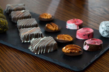 Plate with gourmet chocolates on wooden table