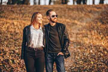 Beautiful young couple walking in the autumn park on a sunny day